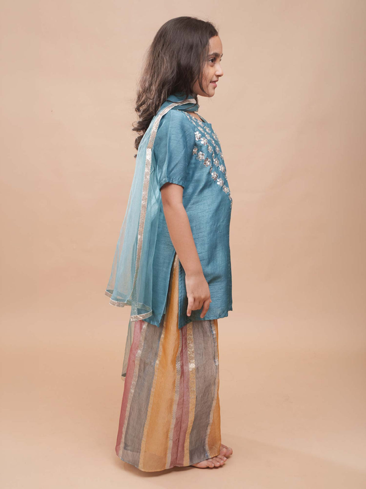 Girls teal blue silk festive ethnic wear set featuring a hand-embroidered kurti and wide-leg striped sharara trousers by StorytellersJunior.