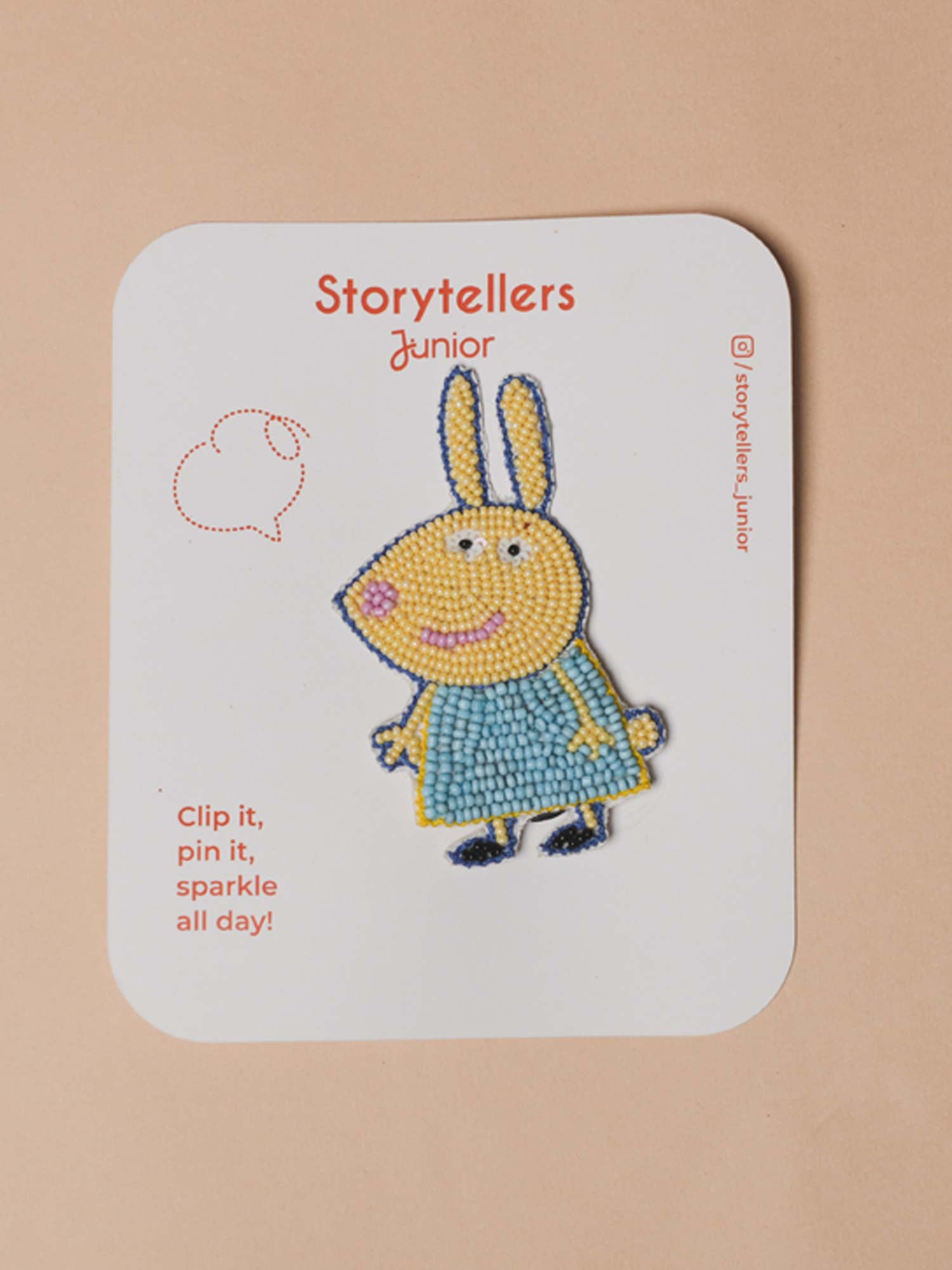 Rebecca Rabbit brooch pin handcrafted with yellow and blue glass beads displayed on a StorytellersJunior branded product backing card.