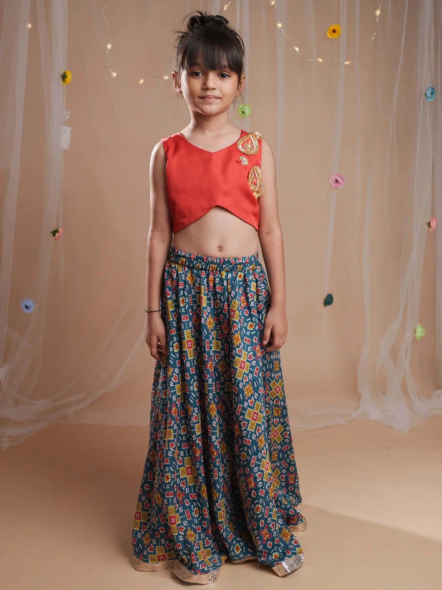 Young girl wearing the Rangrez red silk blouse with gota embroidery and multicolor ikat lehenga skirt by StorytellersJunior.