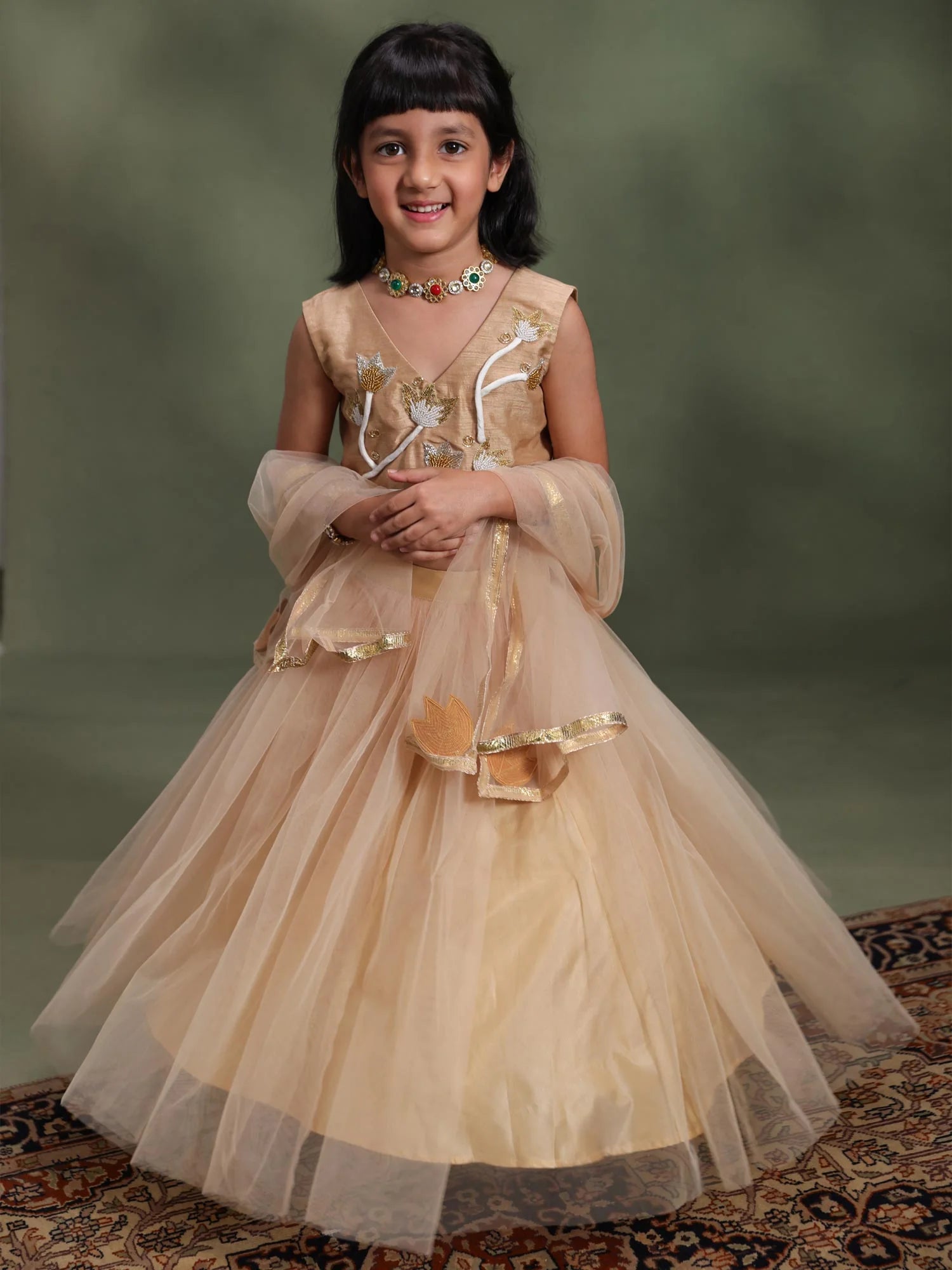 Girl wearing Storytellers Junior Suhana Golden Taari Lehenga Set with Taari work blouse and tulle dupatta