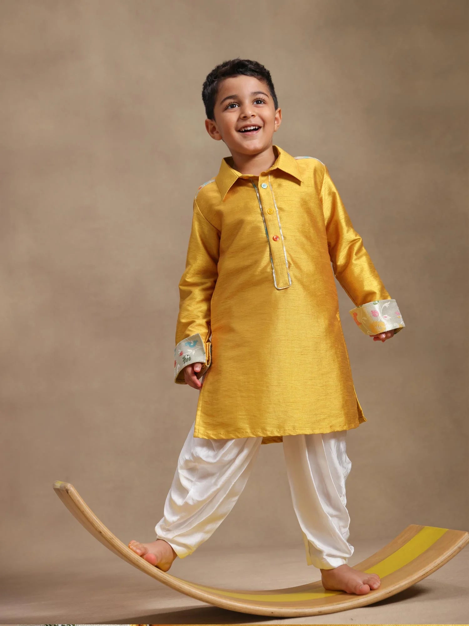 Boy wearing Storytellers Junior Tej Mustard Kurta Dhoti Set with printed cuffs and white cowl pants