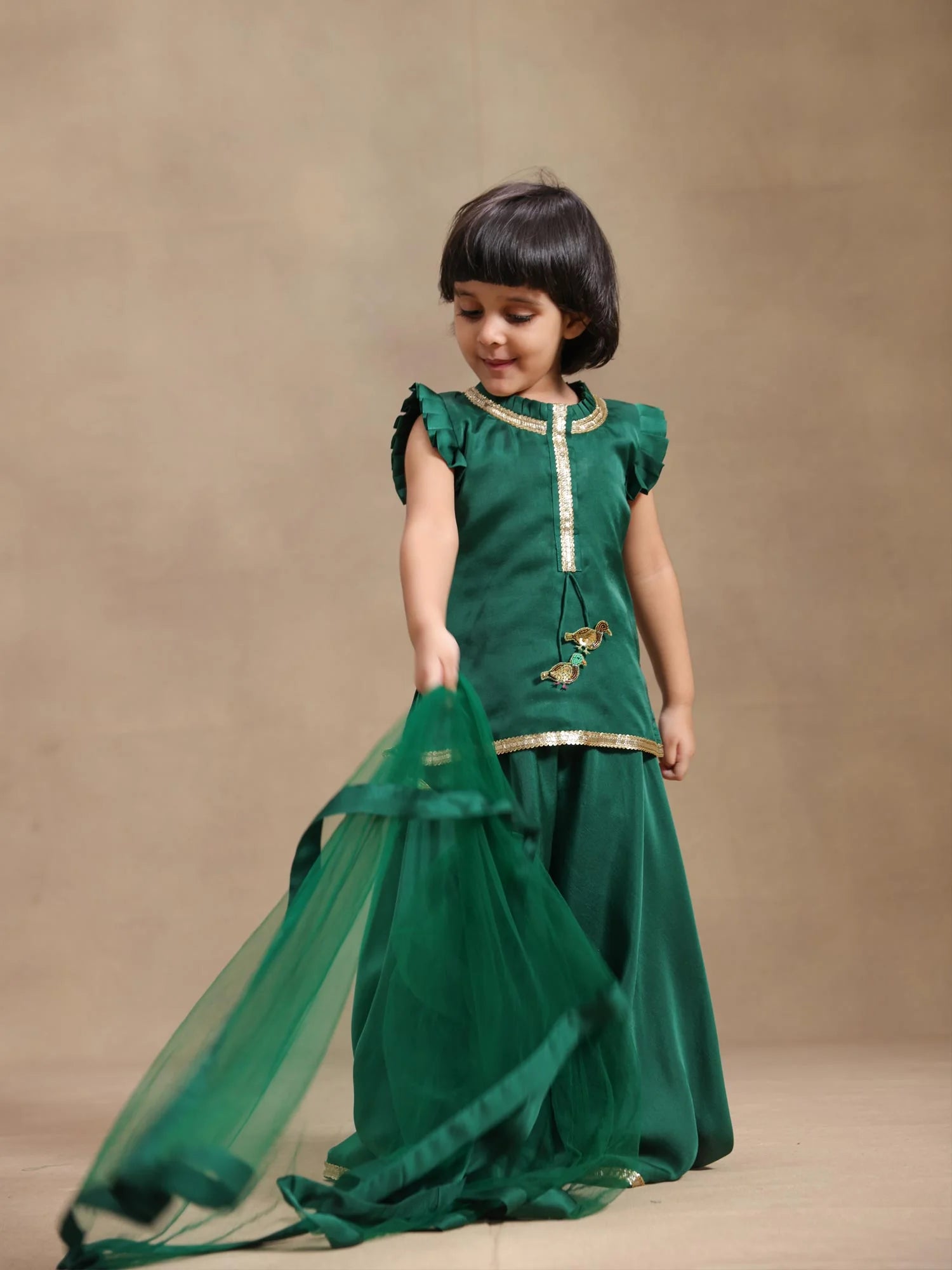 Girl wearing Storytellers Junior Mira Emerald Bird Sharara Set in green with bird motifs and tulle dupatta