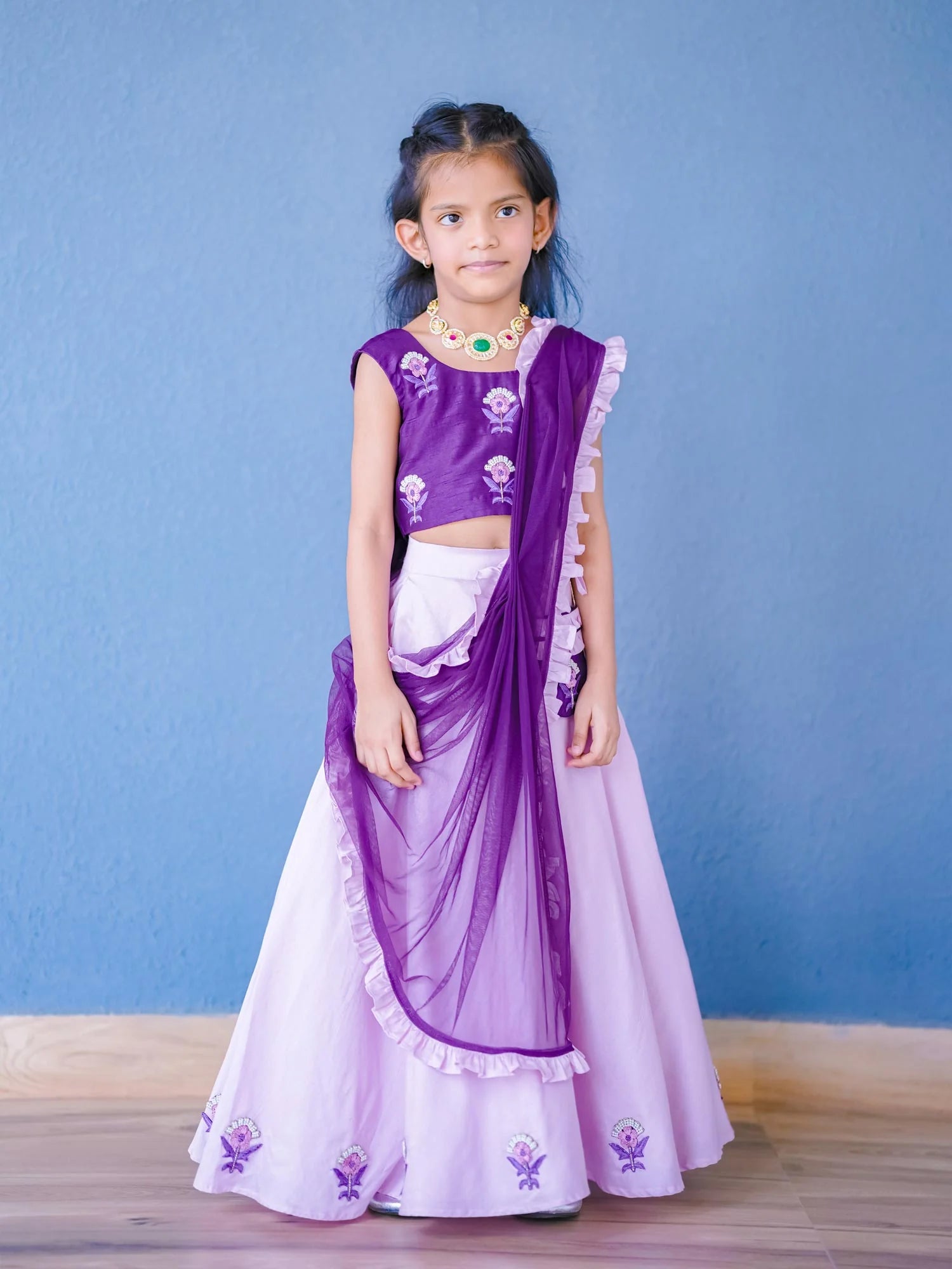Girl wearing Storytellers Junior Pari Lavender Lehenga Choli Set with floral embroidery and ruffle dupatta