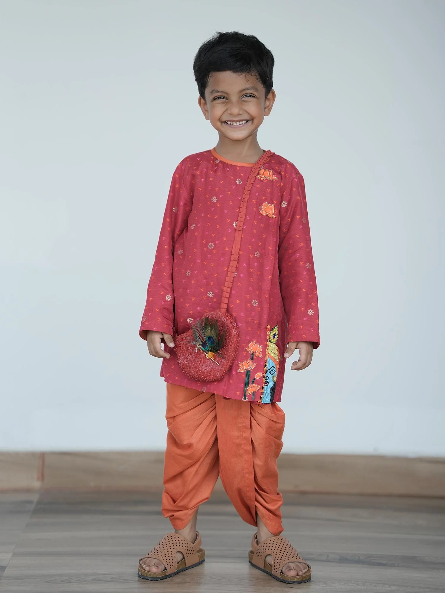 Boy wearing Storytellers Junior Krishna Dhoti Kurta Set in red and orange for Janmashtami
