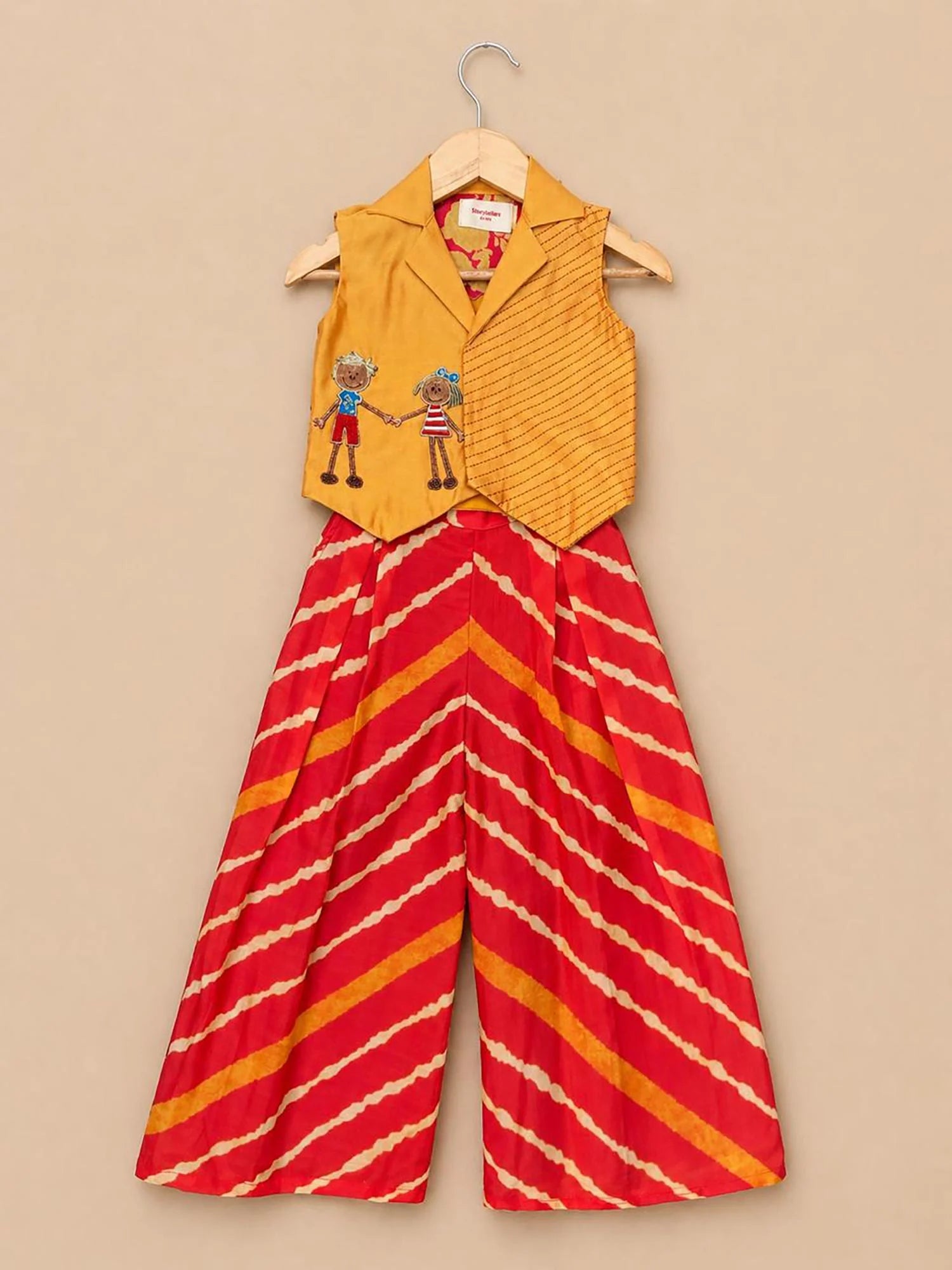 Girl wearing Storytellers Junior Diya Leheriya Co-Ord Set in orange with embroidered mustard waistcoat