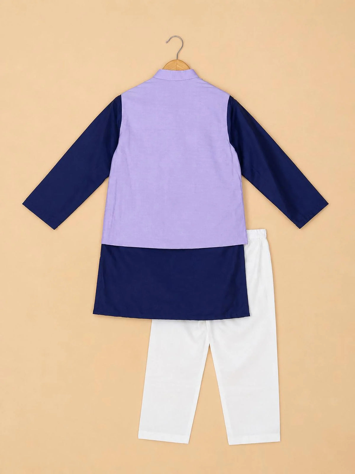 A children's three-piece outfit displayed on a wooden hanger against a solid beige background. The set includes a color-blocked long-sleeve kurta with a lavender purple upper section and navy blue lower section and sleeves, paired with white pants.